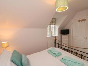 a bedroom with a bed with white sheets and blue pillows at Dotty's Sunshine Cottage in Reighton +30 photos