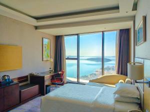 黄岛青岛西海岸喜来登酒店的一间配有床、书桌和大窗户的酒店房间