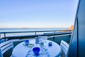 - une table avec des verres bleus sur un balcon avec vue sur l'océan dans l'établissement Appartement avec balcon vue mer, pour 4 personnes, à Dinard