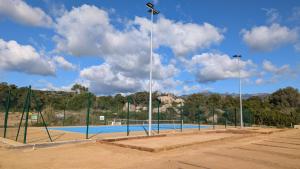 una pista de tenis con luces en el lateral. en La Parenthèse Corse - T2 cabine vue mer, en Pianottoli-Caldarello