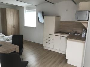 a small white kitchen with a sink and a table at Pension Kaiser in Haldensleben +2 photos