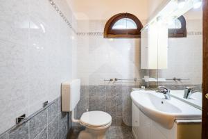 a white bathroom with a toilet and a sink at Homiday - Tuscany House - Parcheggio e Giardino Privato in Pisa +17 photos