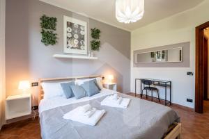 a bedroom with a large bed with two towels on it at Homiday - Tuscany House - Parcheggio e Giardino Privato in Pisa
