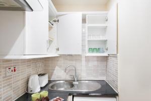 ロンドンにあるEuston Budget Apartments and Roomsの白いキャビネットとシンクのあるキッチン +48枚の写真