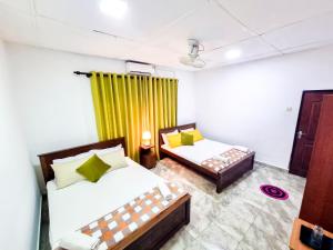 a bedroom with two beds and a yellow curtain at HOSTEL KATUNAYAKE At COLOMBO AIRPORT TRANSIT in Katunayake