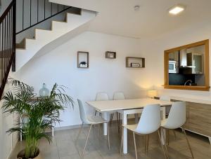 a dining room with a table and white chairs at Villa Son Saura in Cala en Forcat