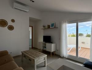 a living room with a couch and a television and a balcony at Villa Son Saura in Cala en Forcat