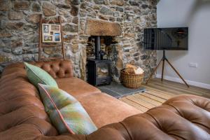 - un canapé dans le salon doté d'une cheminée en pierre dans l'établissement Armadale Farm Cottage, à Armadale
