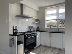 a kitchen with a black stove and a sink at Spacious house next to the mill! in Westkapelle