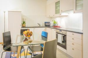 una cocina con una mesa de cristal con un bol de fruta en Los Lorentes Residences Bulle, en Bulle