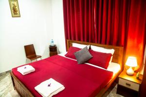 a bedroom with a red bed with red curtains at HOSTEL KATUNAYAKE At COLOMBO AIRPORT TRANSIT in Katunayake