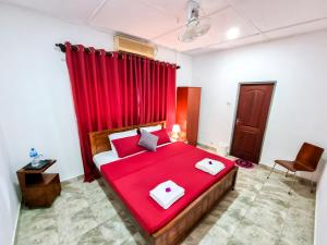 a bedroom with a red bed with a red curtain at HOSTEL KATUNAYAKE At COLOMBO AIRPORT TRANSIT in Katunayake