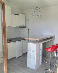 a kitchen with white cabinets and a table with a red stool at Charming apartment with sea view in Sumartin - 27 sqm in Sumartin