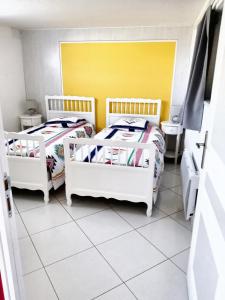 a room with two beds and a yellow wall at Maison charmante à Trédaniel avec jardin et terrasse in Trédaniel