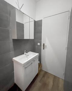 a white bathroom with a sink and a mirror at Confort 6 pers & Wi-Fi rapide in La Courneuve +18 photos