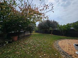a yard with a brick path and trees and a fence at Bright & Cozy Studio - Private Access & Full Privacy in Auckland