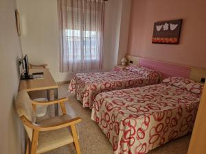 a hotel room with two beds and a desk at Hostal Talavera in Talavera la Real