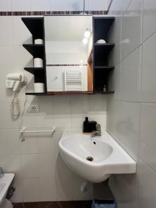 a white bathroom with a sink and a mirror at casadiviaappia in Imola