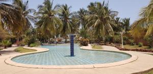 a swimming pool with palm trees in a resort at Résidence safari village in Saly Portudal