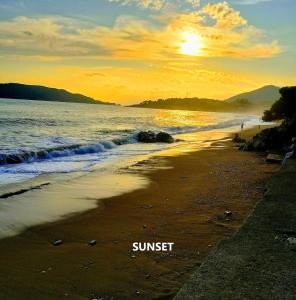 a sunset on a beach with the words sunset at Sea & Mountain View Apartment in Budva +1 photo