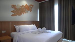 a hotel room with a bed with white sheets at Lakeside TELL Cikarang in Ceper 2 +18 photos