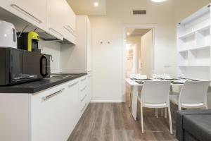 una cucina con mobili bianchi e un tavolo con sedie di Lumen - Downtown Vibes a Cagliari Altre 6 foto