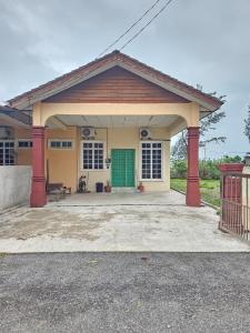 Casa pequeña con puerta verde y patio en Mumtaz Beach Homestay, en Dungun