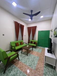 sala de estar con 2 sofás verdes y TV en Mumtaz Beach Homestay, en Dungun