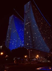two tall buildings lit up in blue at night at Orbi City ApartHotel in Batumi