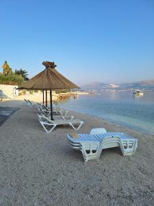 a group of lounge chairs and an umbrella on a beach at Apartman Fishers View in Trogir