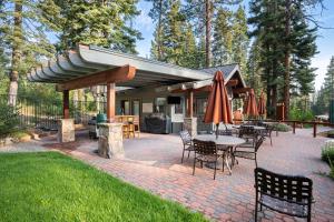eine Terrasse mit Tischen und Stühlen und einem Sonnenschirm in der Unterkunft Flurry by AvantStay Tahoe Donner Home w Access to Northstar Resort Community in Kingswood Estates