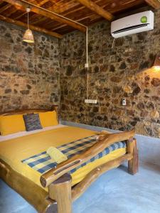 a bedroom with a wooden bed in a stone wall at Lizard Safari Lodge in Udawalawe