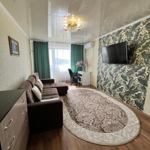 Una sala de estar con un sofá y un televisor de pantalla plana. en Абдирова 37 отличный вариант, en Karagandá