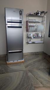 a kitchen with a refrigerator and a shelf with dishes at Village Homestay in Panchgani