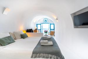 a white living room with a couch and a tv at Nano Oia Villas in Oia