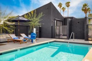 a swimming pool with two chairs and a house at Blackhaus B10 by AvantStay Modern Room Pool in Palm Springs