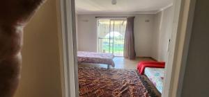 a room with two beds and a window at Tesselaarsdal Backpackers & Koshuis in Caledon