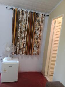 a room with curtains and a fan and a window at Chalé da Vânia in Alto Paraíso de Goiás