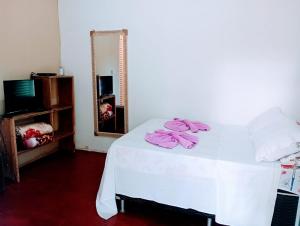 a white bed with pink towels on it in a room at Chalé da Vânia in Alto Paraíso de Goiás