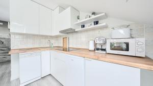 a kitchen with white cabinets and a counter with a microwave at Grunwaldzka, Sun & Snow in Pobierowo
