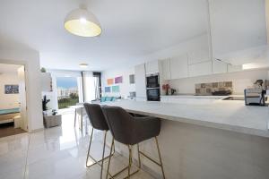 a kitchen with a counter and stools in it at Spacious 2BD Apartment with Large Front Balcony & Country Views - Close to Sea in St Paul's Bay +18 photos