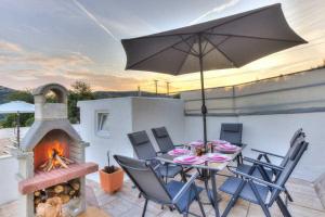 un patio avec une table avec un parasol et une cheminée dans l'établissement Holiday House Pan Franko by aneo travel, à Bribir