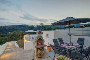 un patio avec une table et un parasol dans l'établissement Holiday House Pan Franko by aneo travel, à Bribir