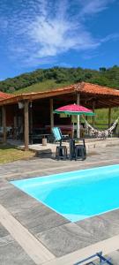 a pool with two chairs and a table and a umbrella at sitio santa Eulalia in Cunha