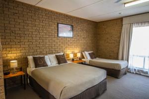 マナムにあるMannum Motelのレンガの壁のホテルルームで、ベッド2台が備わります。