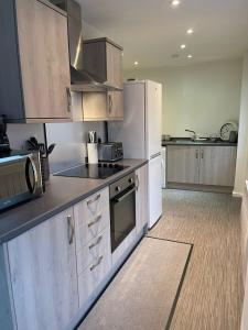 a kitchen with white appliances and wooden cabinets at Coronation Court in Stoke on Trent