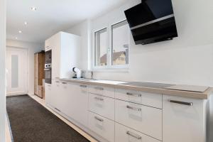 a kitchen with white cabinets and a tv on the wall at Ferienwohnung König in Lustenau