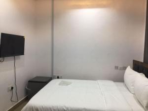 Schlafzimmer mit einem weißen Bett und einem Flachbild-TV in der Unterkunft Babcock University House in Lagos