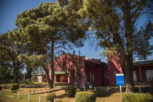 a red building with trees in front of it at La Posta Hotel de Campo in Tres Lomas +3 photos