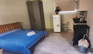 a bedroom with a blue bed and a refrigerator at Suíte Parque Barigui in Curitiba